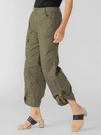 Woman wearing olive green cargo pants with rolled-up hems and black heeled sandals against a plain background