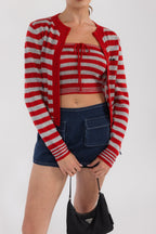 Woman wearing red and gray striped cropped tube top and matching cardigan with denim mini skirt holding a black handbag