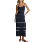Woman wearing a navy blue striped maxi dress with thin straps and white triangular patterns, styled with sandals