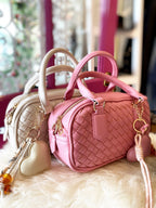 Pink and cream mini woven vegan crossbody bags with handles and removable straps on a soft surface.