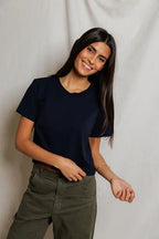 Smiling woman wearing a simple navy blue tee and olive green pants in a casual women's clothing style