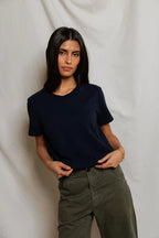 Woman wearing a dark navy short-sleeve tee paired with olive green pants against a neutral backdrop