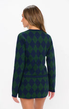 Woman wearing green and navy argyle knit cardigan shown from back in women's clothing style