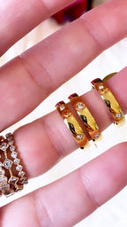 Close-up of gold chunky stacker rings with embedded crystals worn on a woman's fingers for fashion jewelry.