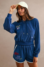 Woman wearing a blue terry hoodie and matching shorts with beach-inspired embroidery in casual women's clothing