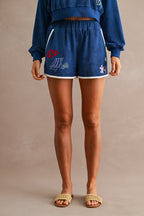 Woman wearing navy blue terry cloth shorts with elastic waistband and embroidered beach-themed designs