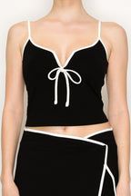 Woman wearing black fitted tank top and wrap-style skort with white trim, casual women's clothing
