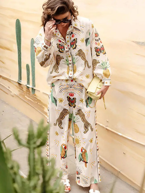 Woman wearing oversized button-down blouse and pants with tropical and animal prints in neutral tones