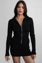 Woman wearing a fitted black knit zip-up hoodie and matching mini skirt as women's clothing outfit