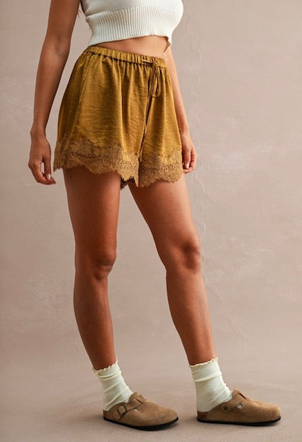 Woman wearing mustard lace-trimmed drawstring shorts paired with white cropped socks and brown slip-on shoes.