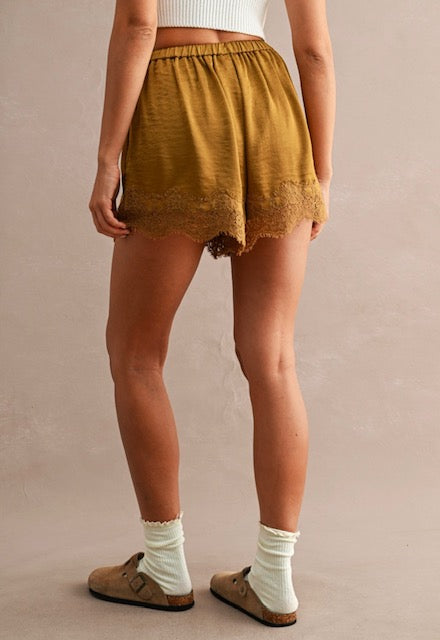 Woman wearing mustard lace-trim shorts with elastic waistband and white socks in a neutral setting