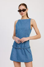 Woman wearing sleeveless denim mini dress with belt detail and black sunglasses modeling women's clothing