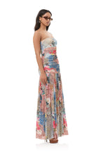 Woman wearing a strapless, colorful patchwork maxi dress with floral and abstract patterns, styled with sunglasses and earrings