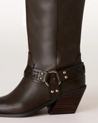 Close-up of brown leather women's boot with decorative strap and stacked heel.