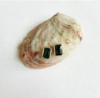 Rectangular green stud earrings displayed on a natural seashell background for women's fashion.