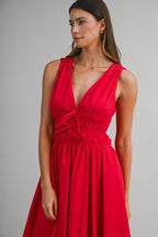 Woman wearing a sleeveless red midi dress with a deep V neckline and ruched waist detail in women's clothing