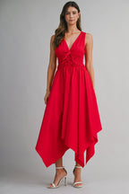 Woman wearing a red sleeveless midi dress with a deep V-neck and asymmetrical hem paired with white heels