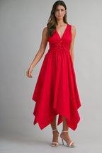 Woman wearing a vibrant red midi dress with a deep V-neck and asymmetric hem, styled with white high heels.