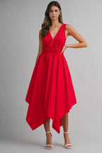 Woman wearing a sleeveless red midi dress with an asymmetrical hem and deep V-neck, styled with white heels