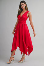 Woman wearing a sleeveless red midi dress with handkerchief hem and white high-heeled sandals modeling women's clothing.