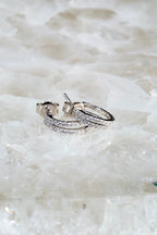 Sterling silver double huggie earrings with sparkling stones on a textured white surface.