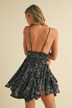Woman wearing a black floral ruffle romper with thin straps and an open back, part of women's clothing collection.