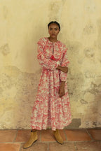 Woman wearing a long bohemian pink and cream patterned maxi dress with ruffled sleeves and ankle boots