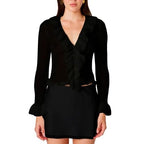 Woman wearing black loosely knit cardigan with ruffled neckline and sleeve openings, paired with a black skirt