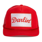 Red foam front trucker hat with mesh back and white patch embroidered with "Darlin'" in script font.