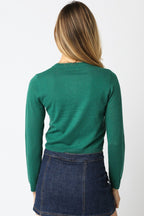 Woman wearing green knit cropped cardigan and denim skirt shown from the back in women's clothing style