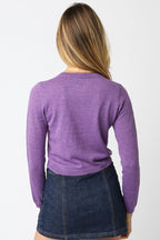 Woman wearing a purple knit cropped cardigan paired with a dark denim mini skirt, viewed from behind.