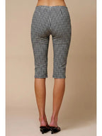 Woman wearing black and white checkered capri pants standing against a beige background