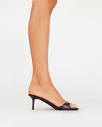 Women's black open-toe mule with a slim heel, styled on a model's foot against a white background