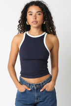Woman wearing a sleeveless navy tank top with white trim paired with casual denim jeans in women's clothing.