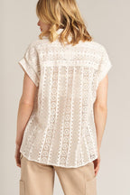 Woman wearing a white short sleeve crochet button down top made of cotton and nylon viewed from the back