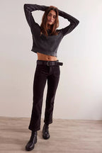 Woman wearing black high-rise kicked flare pants with a belt, paired with a cropped ribbed sweater and black boots.