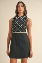 Woman wearing black sleeveless mini dress with sequin embellishments and collar in women's clothing style