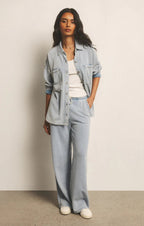 Woman wearing light blue knit denim pants with a matching oversized jacket and white tank top in casual style