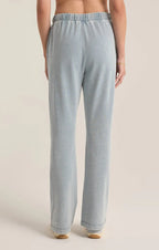 Back view of lightweight knit denim pants with a drawcord waistband, worn by a woman in women's clothing.