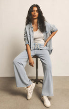 Woman wearing light blue knit denim pants with a drawcord waist, paired with a denim jacket and white sneakers.