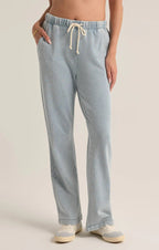 Woman wearing light blue knit denim pants with drawstring waist and pockets paired with casual sneakers
