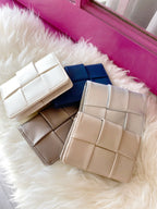 Collection of vegan leather woven wallets in neutral and navy tones displayed on a white fur surface.