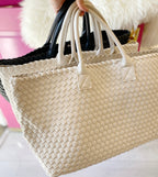 Hand holding woven vegan leather bags in neutral tones, suitable for women's fashion and everyday use.