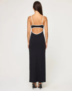 Woman wearing a form-fitting black ankle-length dress with white straps and a back cut-out detail.