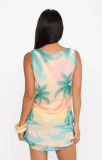 Woman wearing sleeveless dress with tropical palm tree print viewed from the back