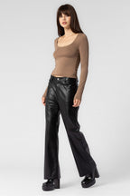 Woman wearing a fitted brown long sleeve top paired with black leather wide-leg pants and platform boots.
