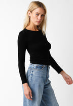 Woman wearing a fitted black ribbed long sleeve top paired with light blue high-waisted denim jeans modeling women's clothing