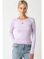 Woman wearing a light purple ribbed long sleeve top paired with blue jeans against a white background.
