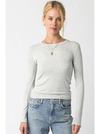 Woman wearing a light grey ribbed long sleeve top paired with blue jeans, styled for casual women's clothing.