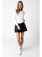 Woman wearing a fitted white long sleeve top with a round neck and a black mini skirt in casual style